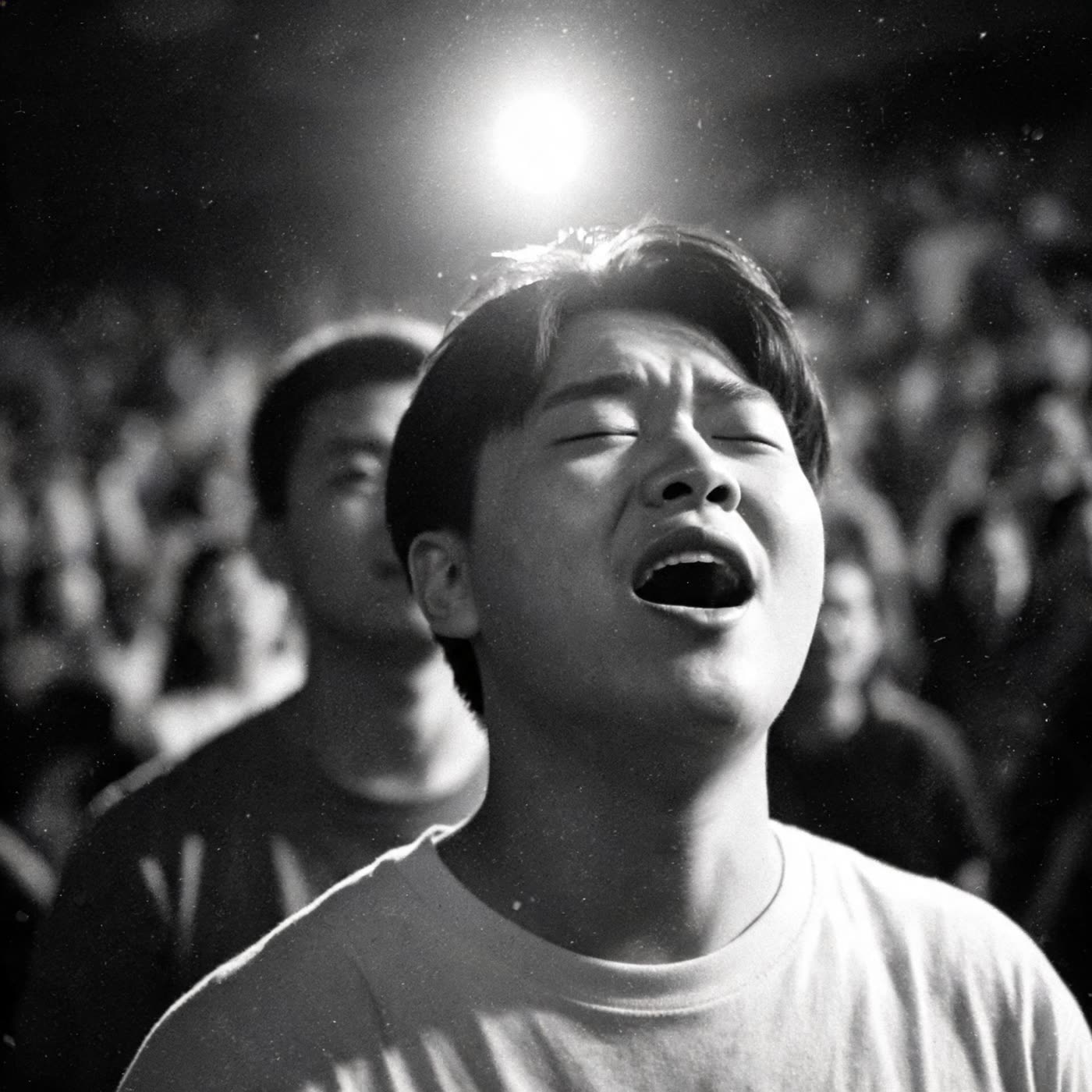 A person singing with eyes closed in a crowded room